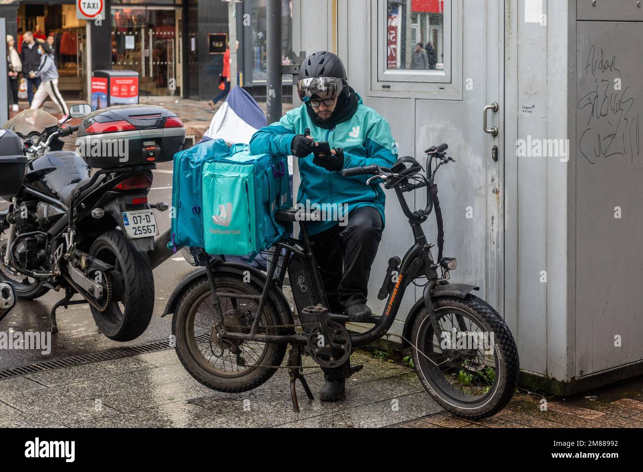 Le pilote Deliveroo fait une pause dans la ville de Cork, en Irlande. Banque D'Images