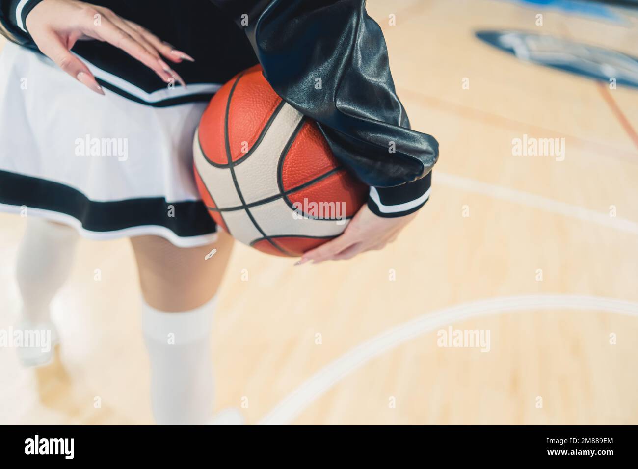 La moitié inférieure d'une meneuse, vêtue d'une mini-jupe ludique, comme  elle tient un basket-ball dans ses mains. Ses jambes sont au centre de la  scène, mettant en valeur son physique tonique et