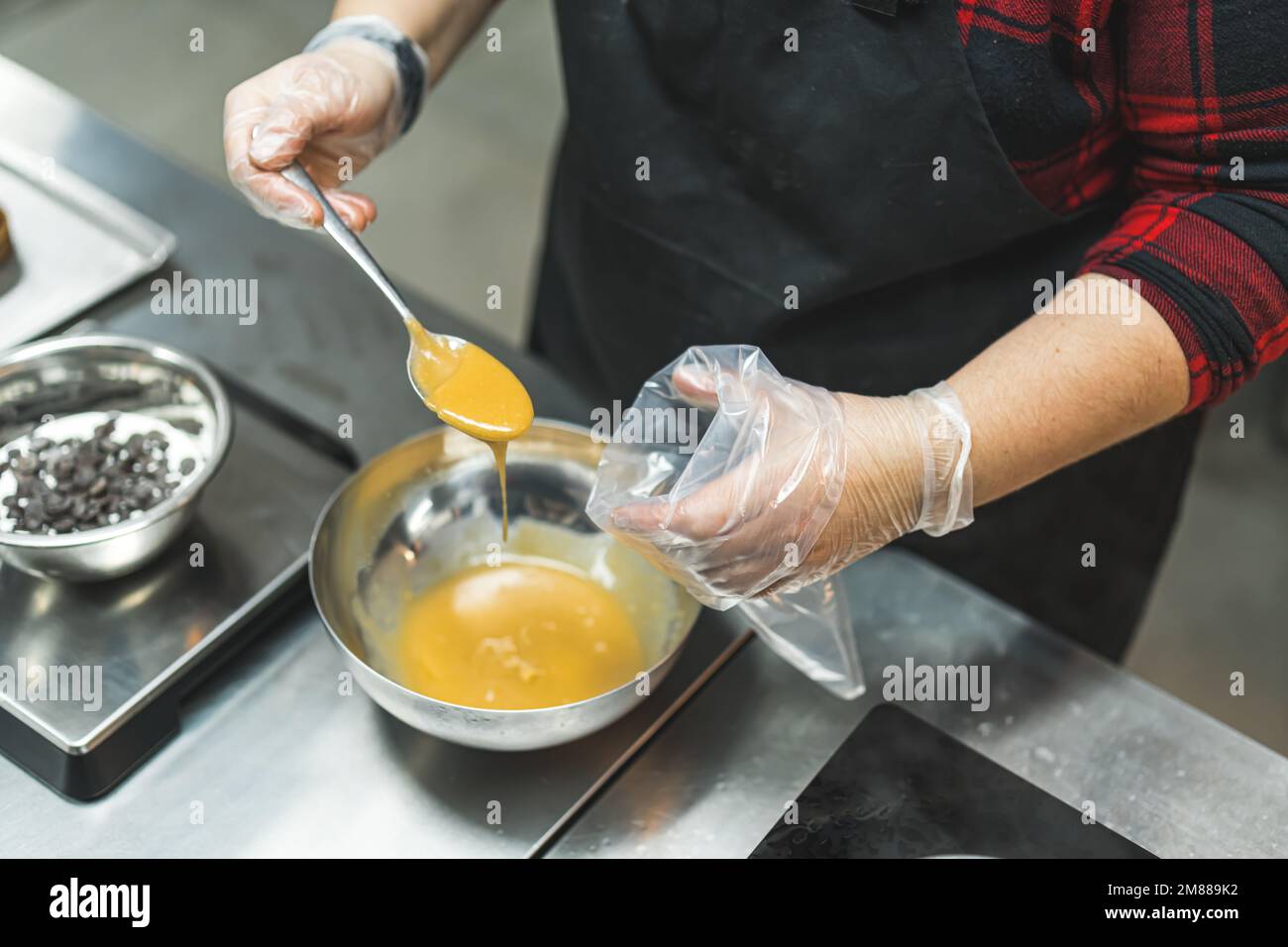 vue de dessus des mains du chef mettant le caramel d'un bol dans un sac de tuyauterie. Photo de haute qualité Banque D'Images