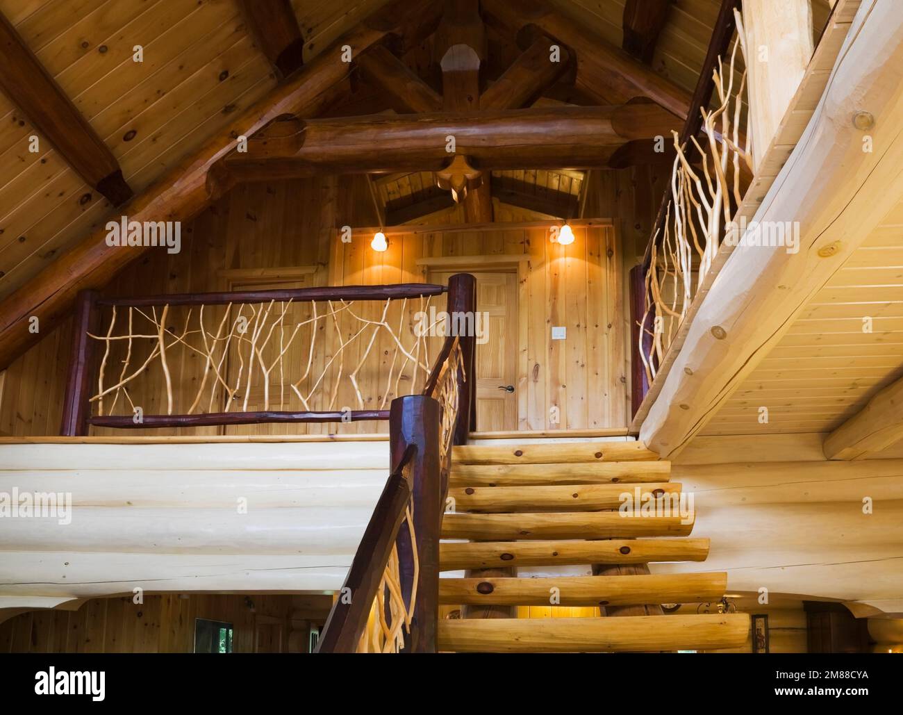 Escaliers en bois de pin blanc avec rambardes de cèdre menant à l'étage supérieur à l'intérieur de la maison en rondins de style scandinave. Banque D'Images
