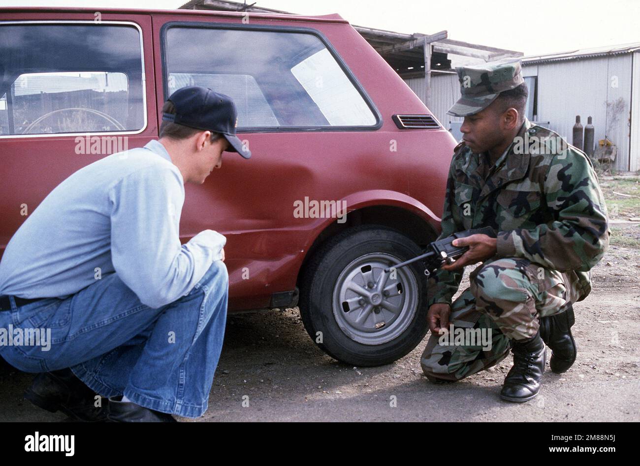 MAÎTRE d'armes 2nd classe David L. Gilbert inspecte les dommages causés à une voiture appartenant à l'un des marins de la gare. Base: Naval Air Station, Sigonella État: Sicile pays: Italie (ITA) Banque D'Images