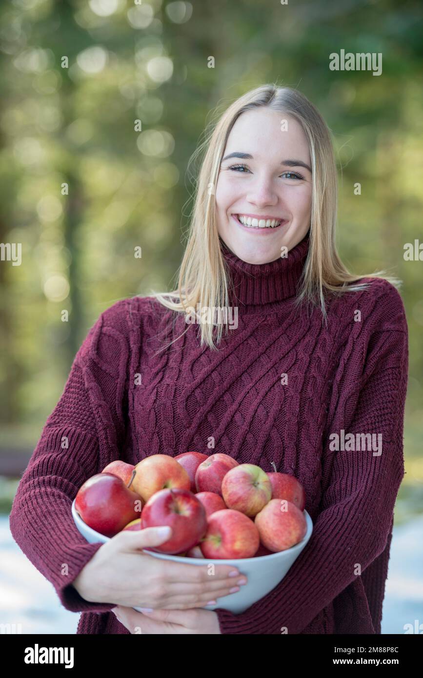Portrait d'une jeune blonde portant un bol de pommes, haute-Bavière, Bavière, Allemagne, Europe Banque D'Images