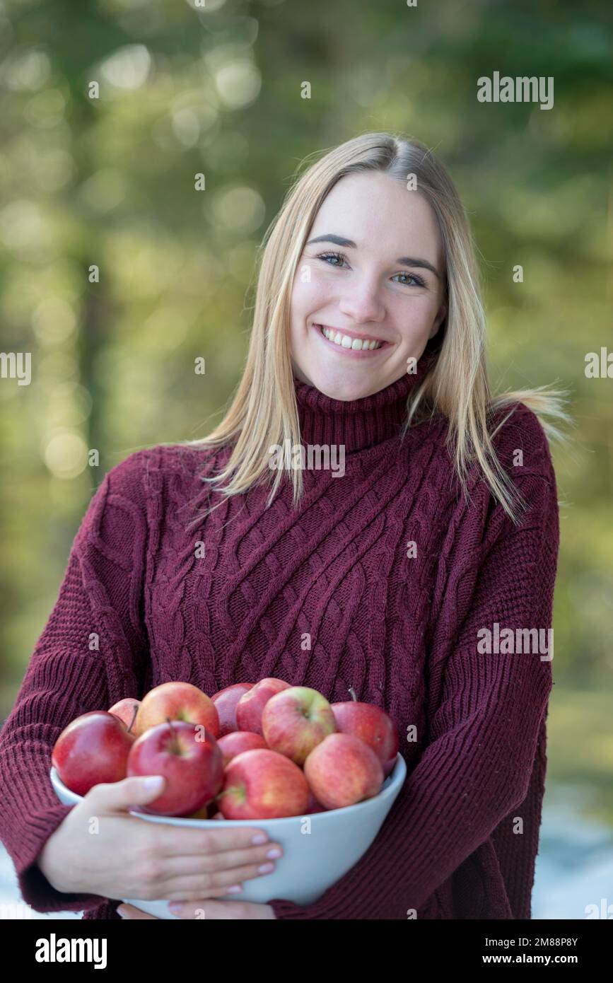 Portrait d'une jeune blonde portant un bol de pommes, haute-Bavière, Bavière, Allemagne, Europe Banque D'Images