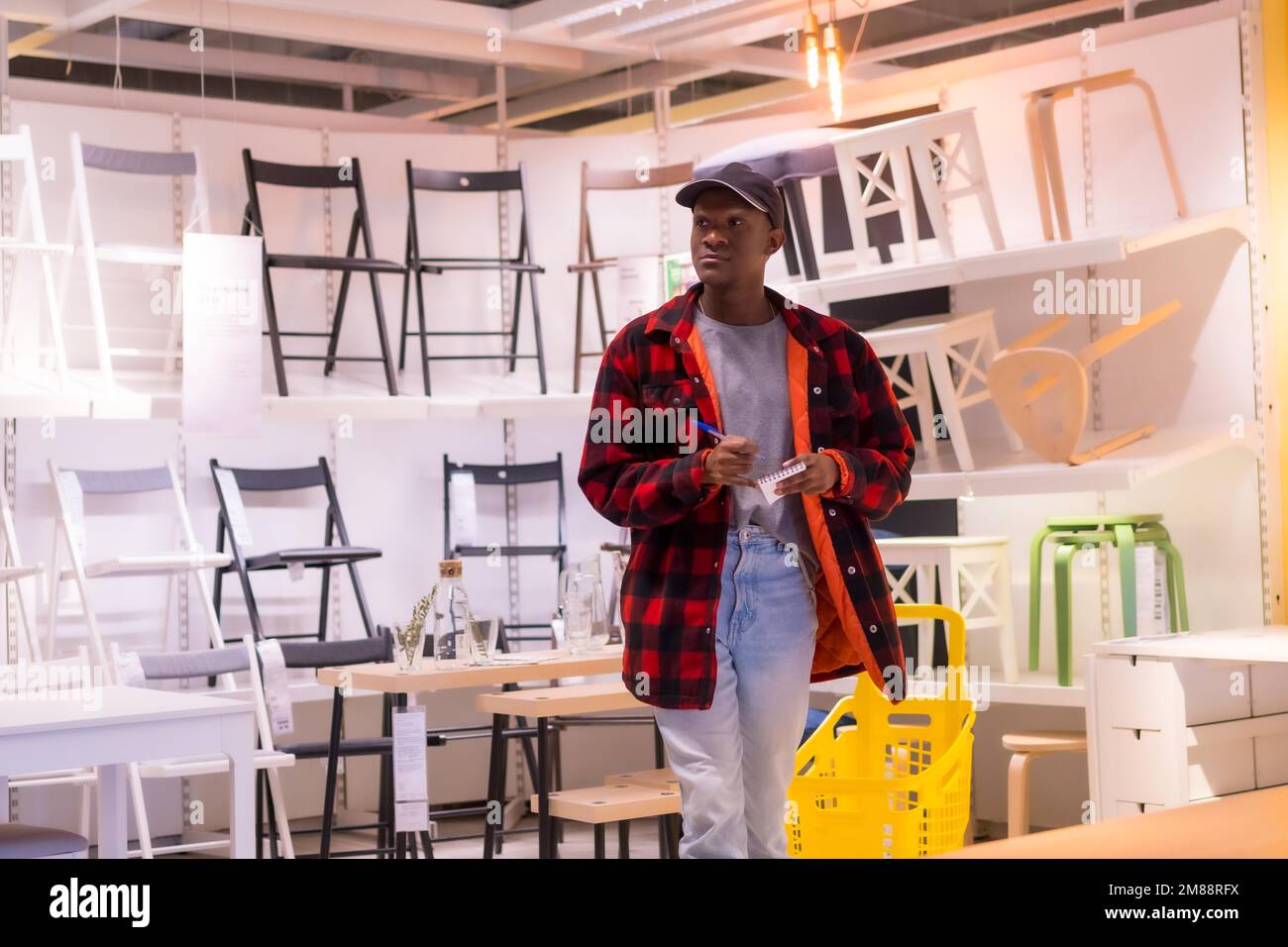 Homme ethnique noir magasiner dans un magasin de meubles, regardant des chaises Banque D'Images