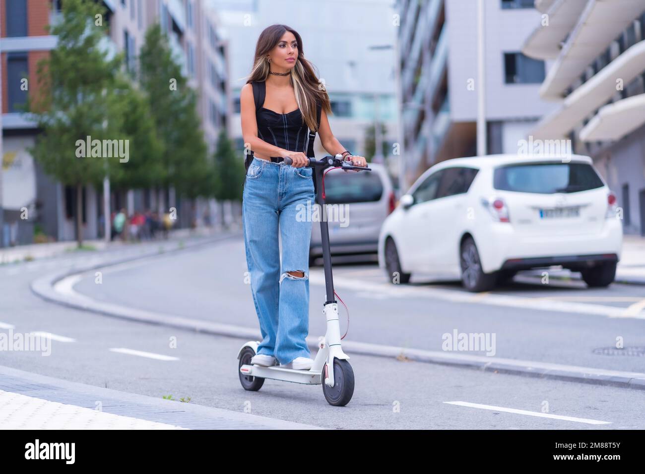 Une jeune brune se déplaçant dans la ville avec un scooter électrique, le  long de la piste cyclable Photo Stock - Alamy