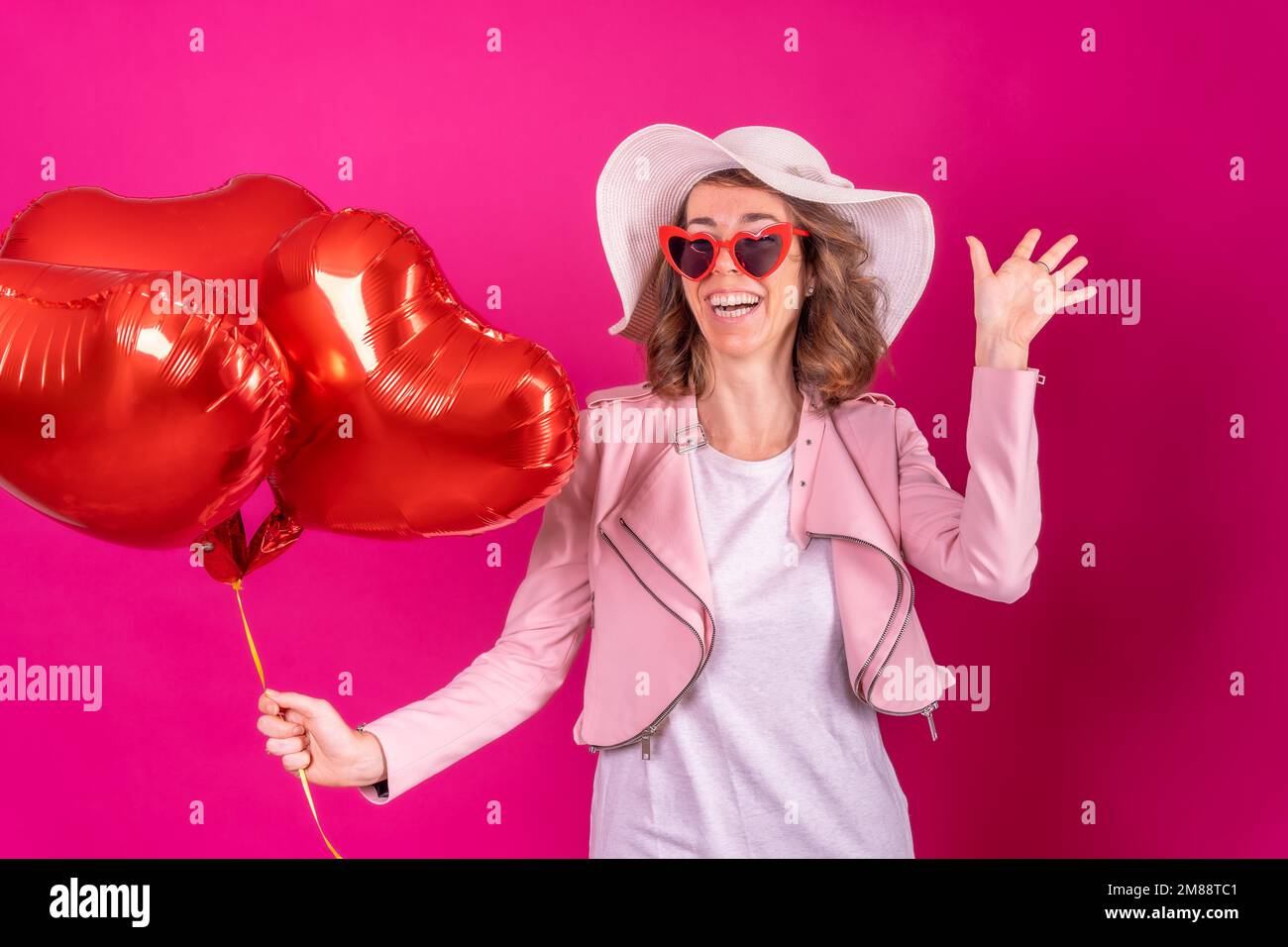 Portrait d'une femme de race blanche qui danse avec un chapeau blanc dans  une boîte de nuit avec quelques ballons de coeur, fond rose Photo Stock -  Alamy