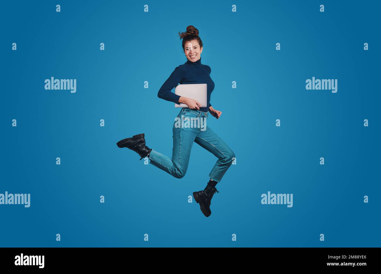 Profil de taille de corps pleine longueur de la femme positive excitée saut haute tenue cahier isolé sur fond bleu de couleur Banque D'Images