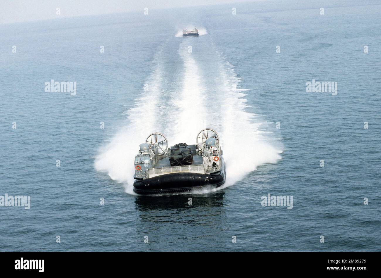 Une vue en arc de l'embarcation à coussin d'air LCAC-12 en cours près de la base navale amphibie, Little Creek, Virginie L'embarcation porte un char de combat principal M-1A1 Marine. Une deuxième LCAC suit dans le sillage de la première. Pays: Chesapeake Bay Banque D'Images