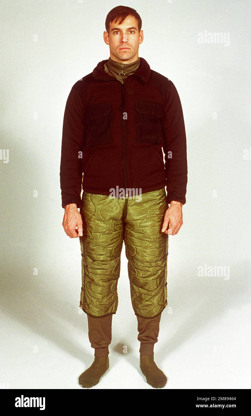 Un soldat s'empare de la veste en fibre polyester et de la doublure de  pantalon de matage en polyester portée avec d'autres éléments du système de  vêtements pour temps froid prolongé (ECWCS).