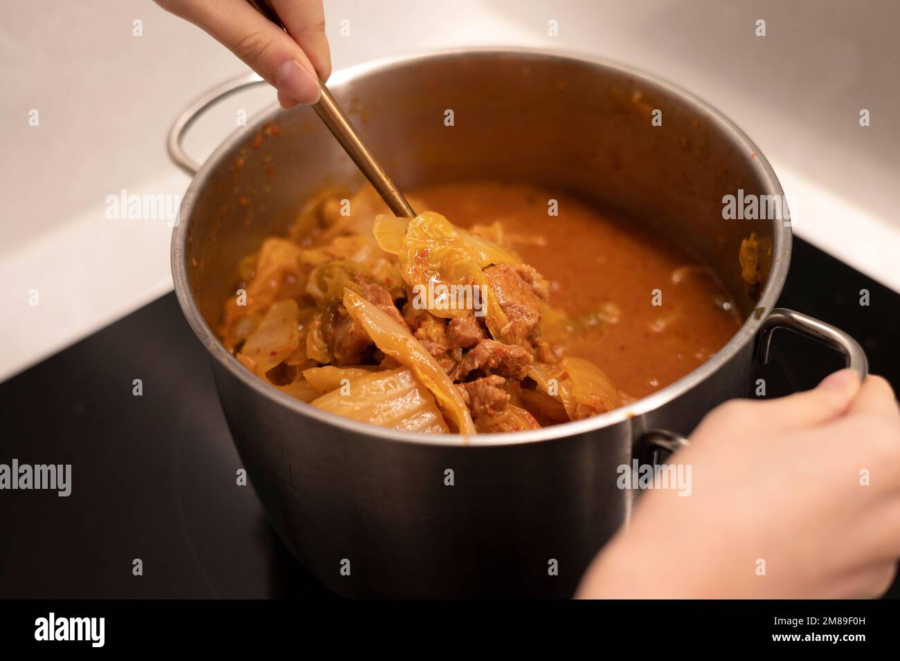 Cuisson du ragoût de kimchi avec une casserole, remuez le ragoût épicé avec une cuillère Banque D'Images