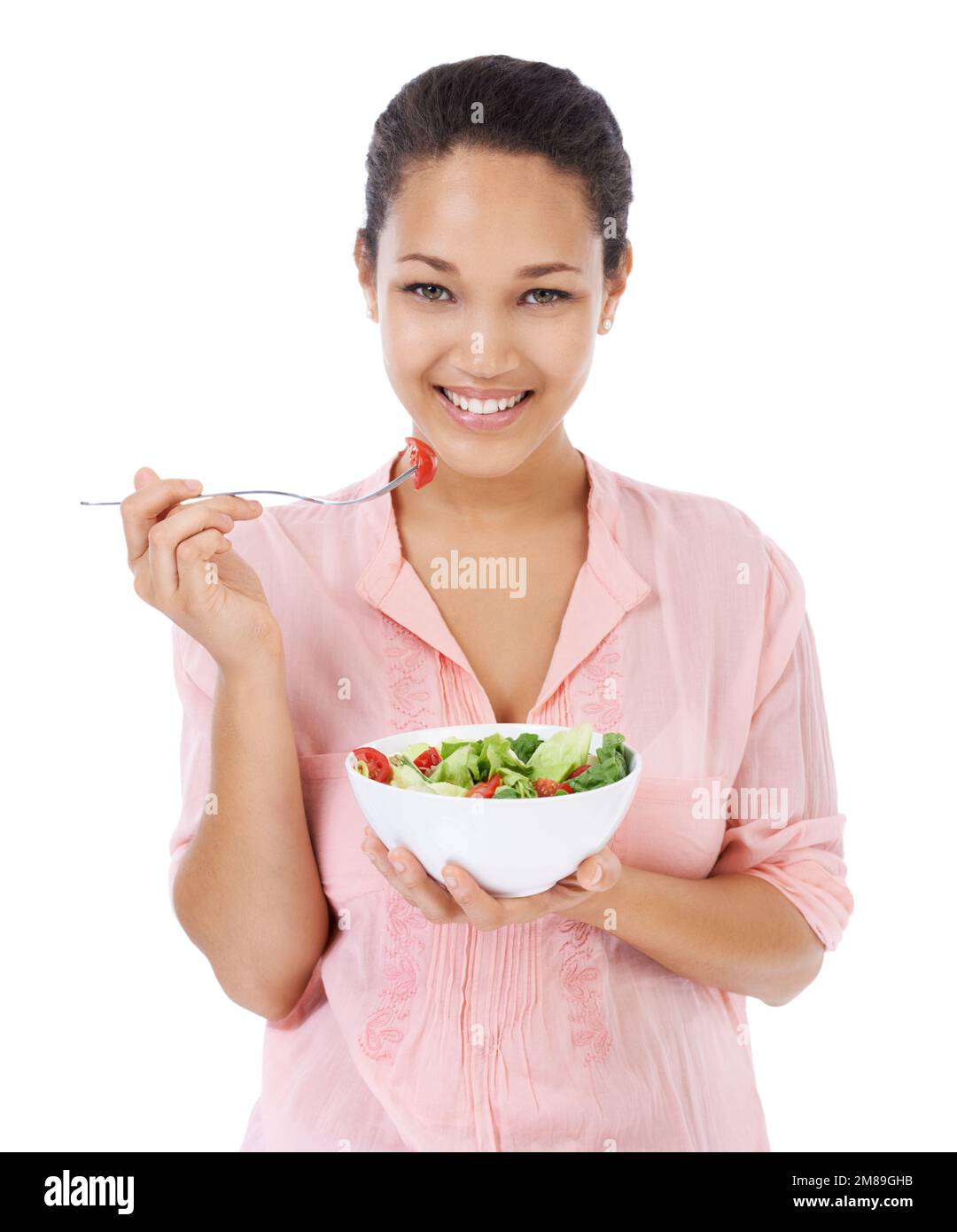 Elle apprécie une alimentation saine. Jeune femme souriant tout en mangeant une salade verte fraîche. Banque D'Images