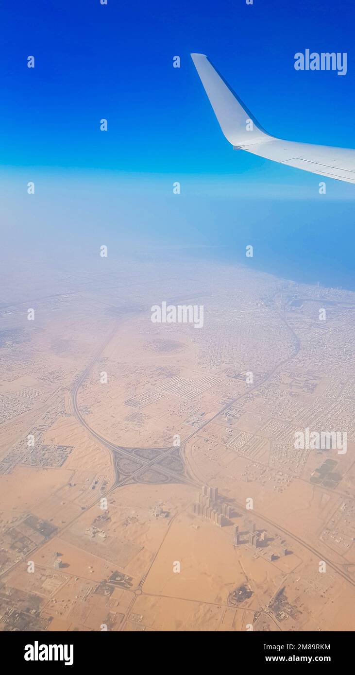 Vue de la fenêtre de l'avion sur le ciel bleu et la terre avec paysage de désert, mer et canaux dans les Émirats. Photo de haute qualité Banque D'Images