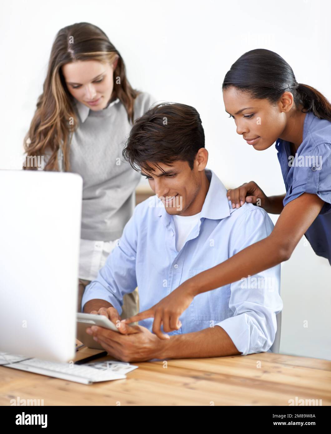 Ils travaillent ensemble pour garantir d'excellents résultats. Un groupe de jeunes entrepreneurs travaillant ensemble sur une tablette numérique. Banque D'Images