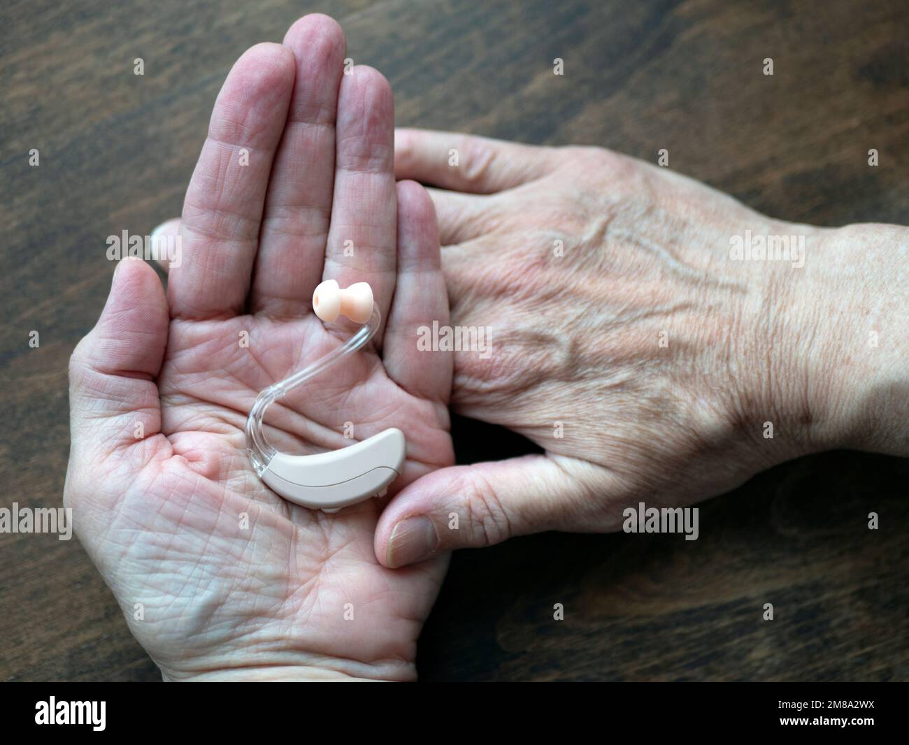 Prothèse auditive dans les mains humaines, mise au point sélective. Appareil médical électronique porté derrière l'oreille Banque D'Images