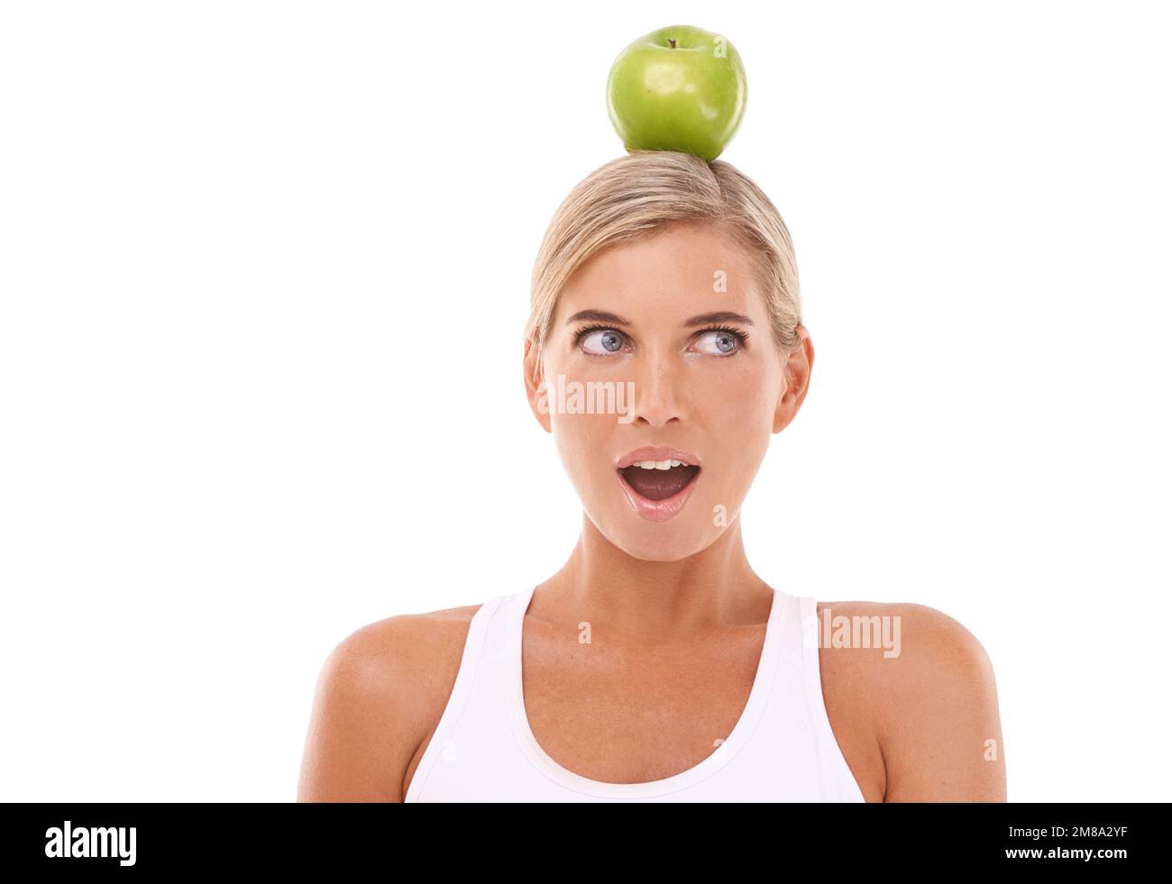 Femme, wow et pomme sur la tête en studio pour le bien-être, le régime et l'équilibre par fond blanc. Modèle isolé, fruit et face d'expression surprise pour Banque D'Images