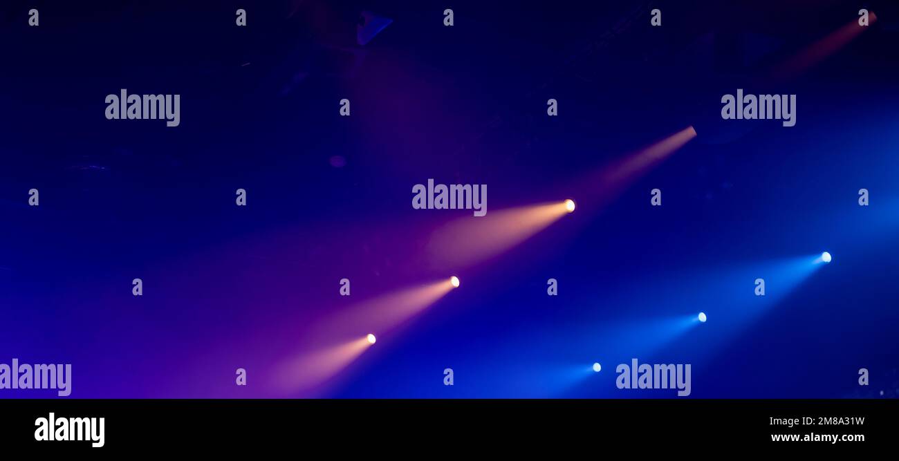 Lumières de spot pittoresques mauves et bleues avec de forts faisceaux de fumée sur fond sombre flou, équipement d'éclairage de scène moderne Banque D'Images