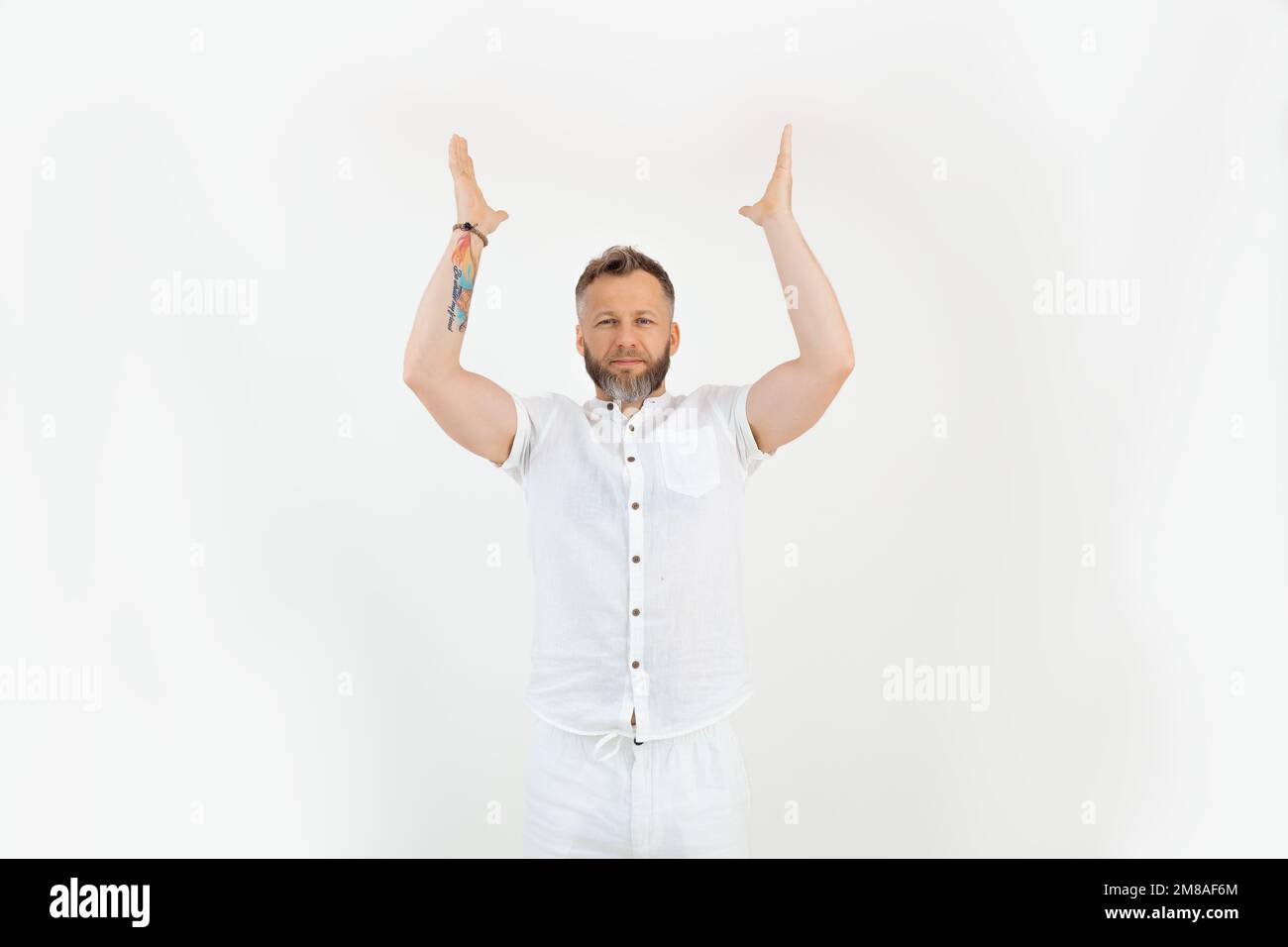 Portrait d'un homme barbu d'âge moyen et confiant debout, levant les mains vers le haut, montrant sur fond blanc. Publicité. Banque D'Images