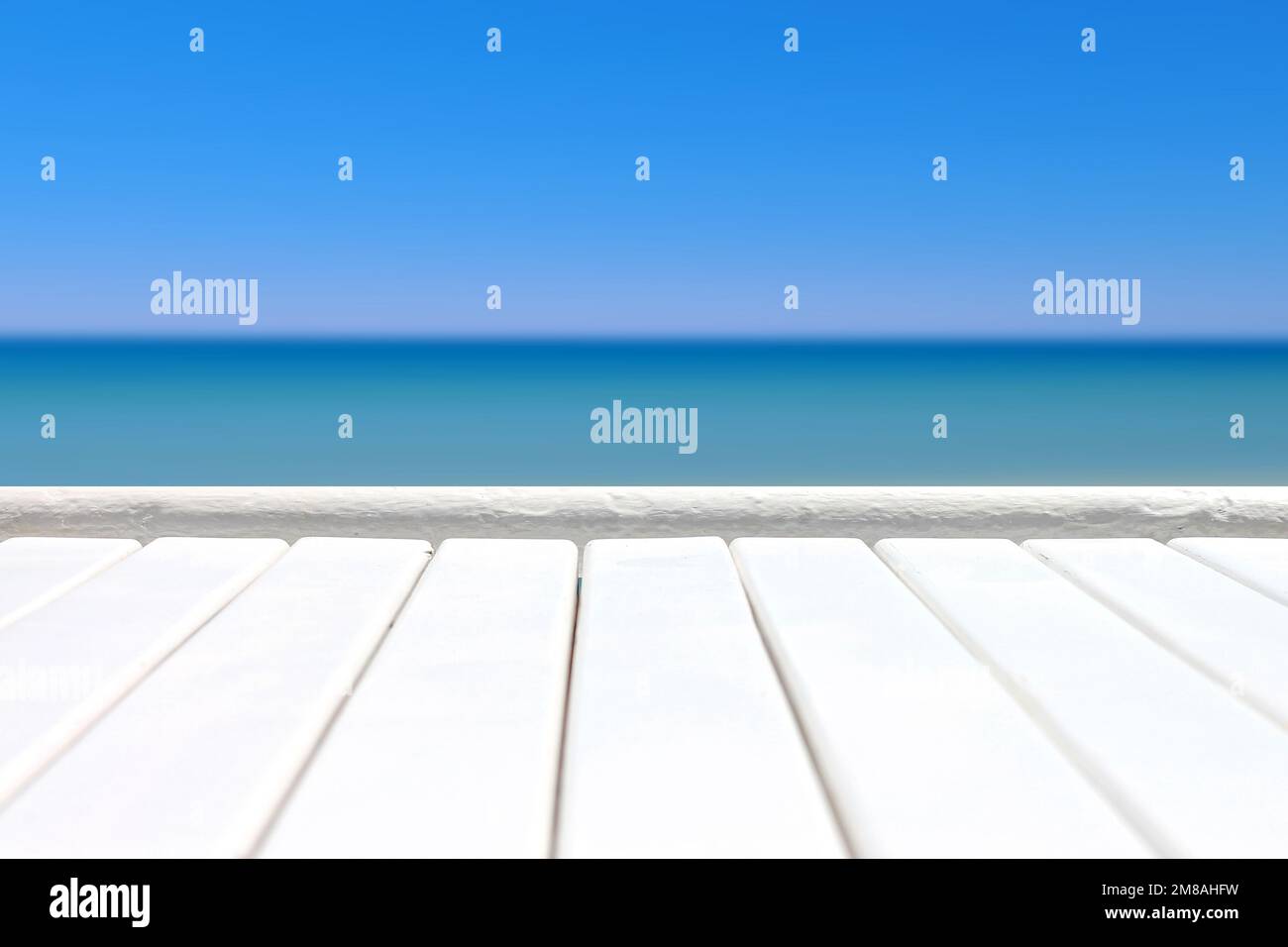 Surface en bois de planche blanche sur fond bleu de mer défocalisé. Banque D'Images
