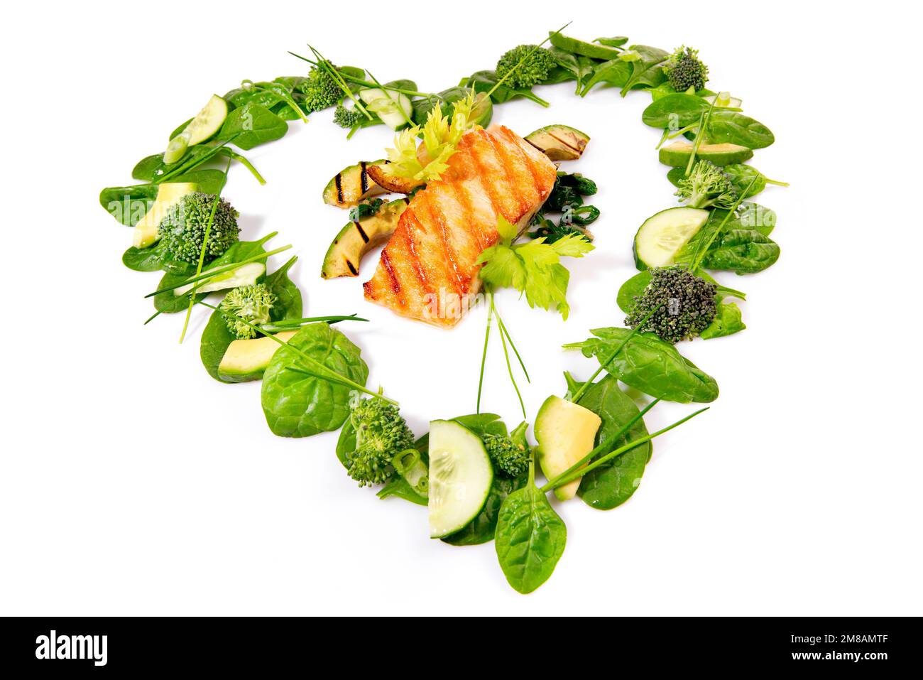Salade verte en forme de coeur et légumes avec saumon grillé isolé sur fond blanc Banque D'Images