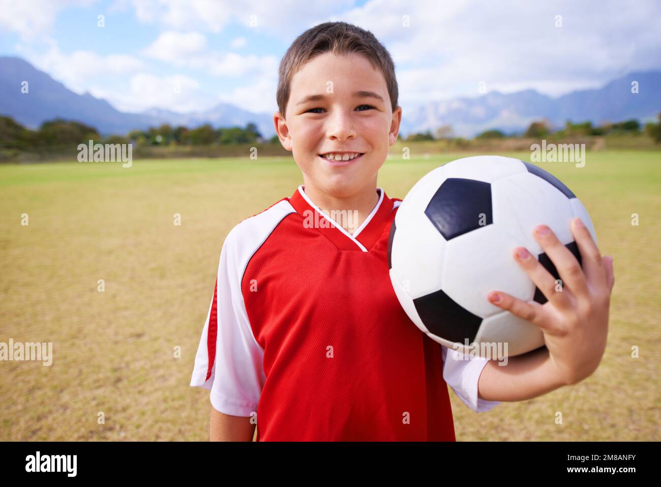Prêt à jouer au football. Gros plan d'un jeune garçon tenant une balle de football. Banque D'Images