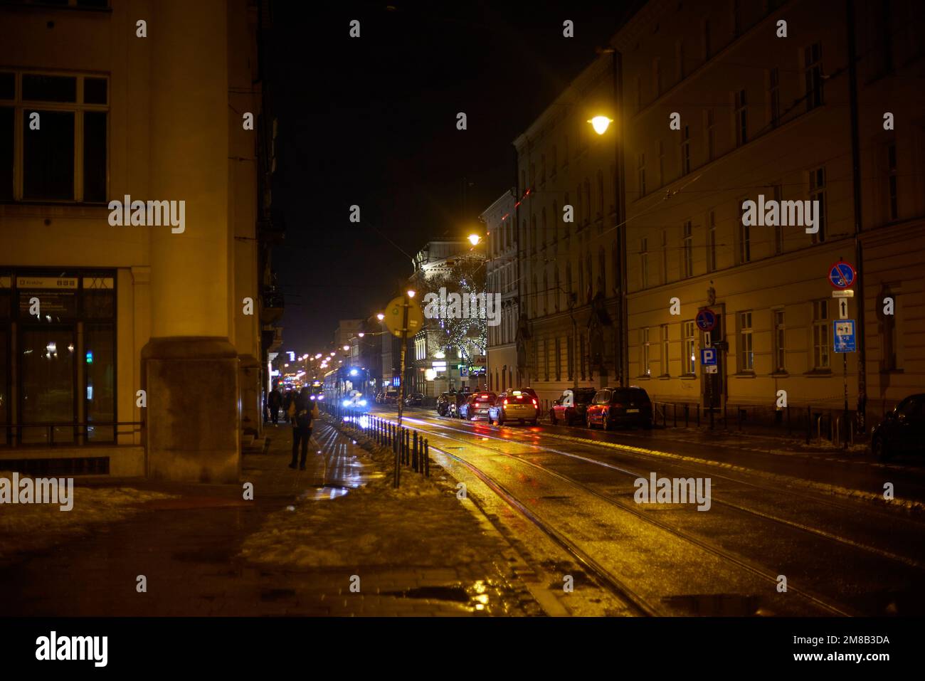 Trafic sur la route de nuit, le tramway traverse les bâtiments de Cracovie, en Pologne. Banque D'Images