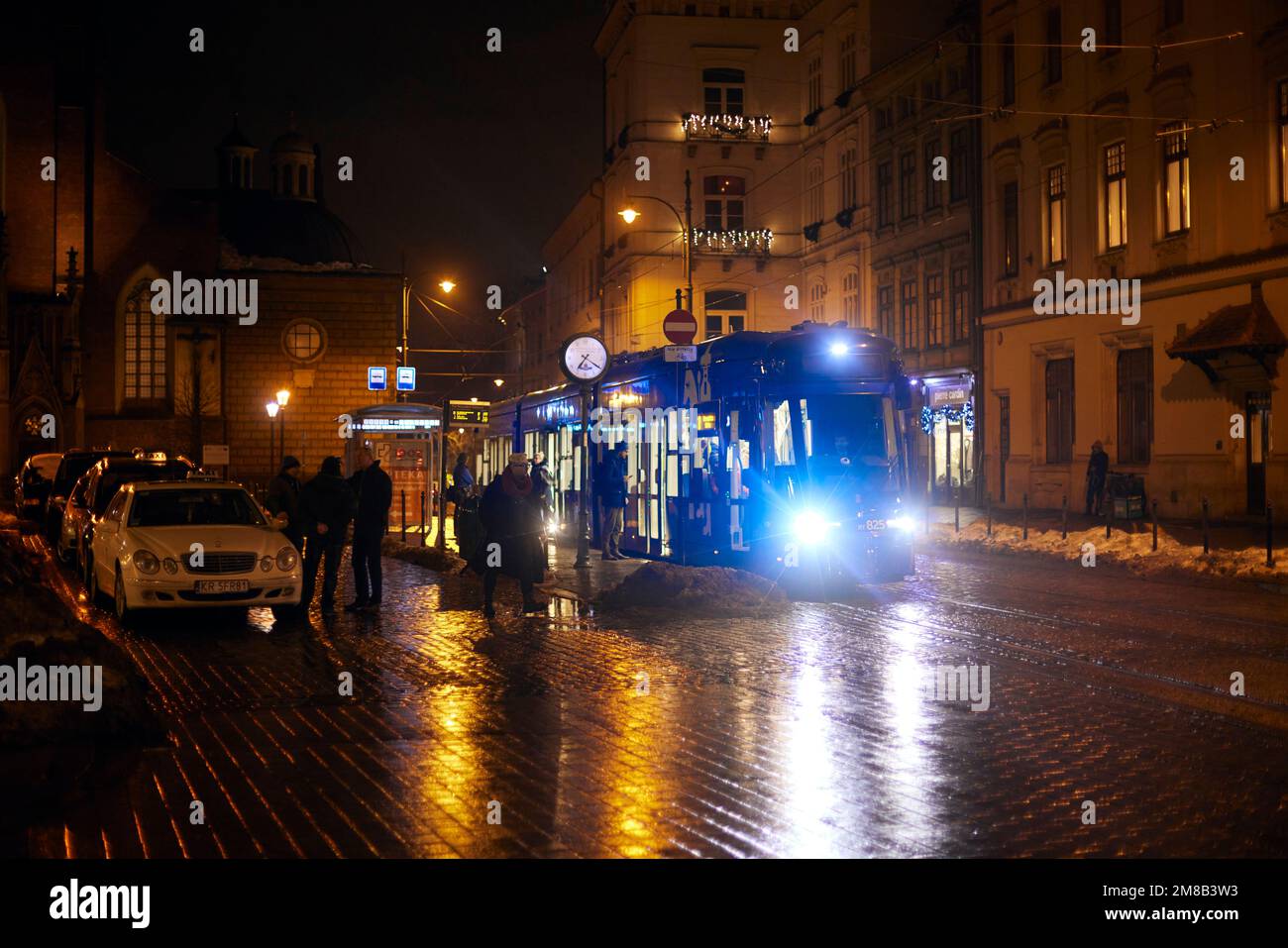 Tram dans la soirée à Cracovie avec les résidents de la ville. Architecture polonaise, lumière orange de lanternes et réflexions. Banque D'Images