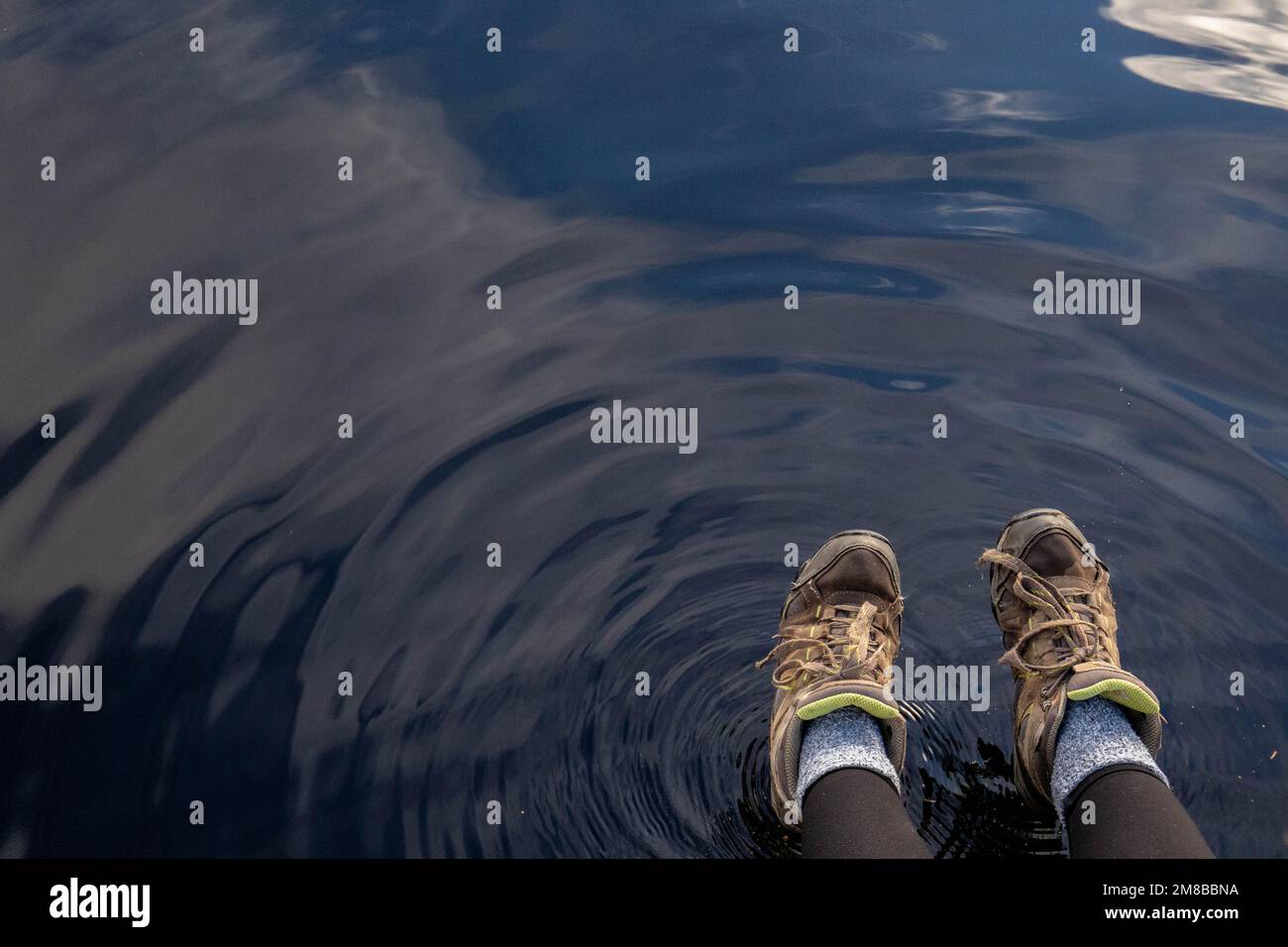 Des bottes de randonnée sur une vague d'eau dans le fond du lac le jour de l'automne Banque D'Images