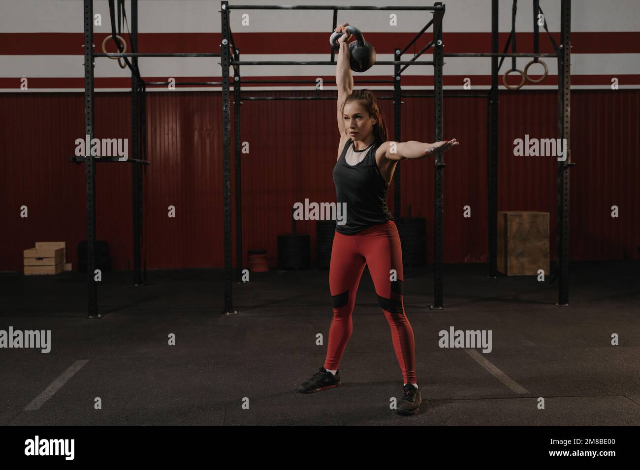 Une jeune femme crossfit soulève une kettlebell lourde à la salle de sport. Athlète de race blanche s'entraîner à la salle de gym. Entraînement avec poids. Banque D'Images