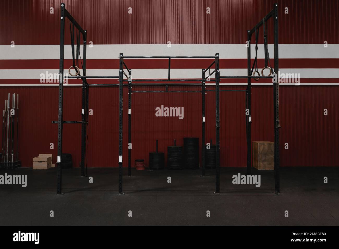Salle de sport CrossFit avec équipement d'entraînement. Barres horizontales, anneaux de gymnastique. Intérieur de la salle de sport de couleur rouge de garage. Banque D'Images
