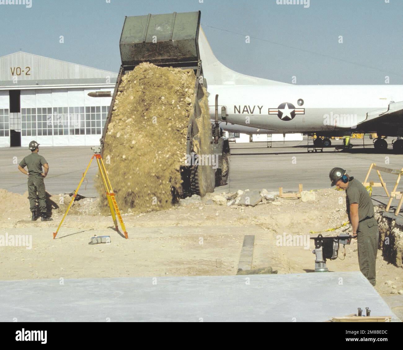 Seabee un camion à benne basculante et un compacteur de sol pour préparer la fondation d'un nouveau bâtiment à l'extérieur d'un hangar de l'escadron 2 de reconnaissance aérienne de la flotte (VQ-2). Date exacte prise de vue inconnue. Base: Station navale, Rota pays: Espagne (ESP) Banque D'Images