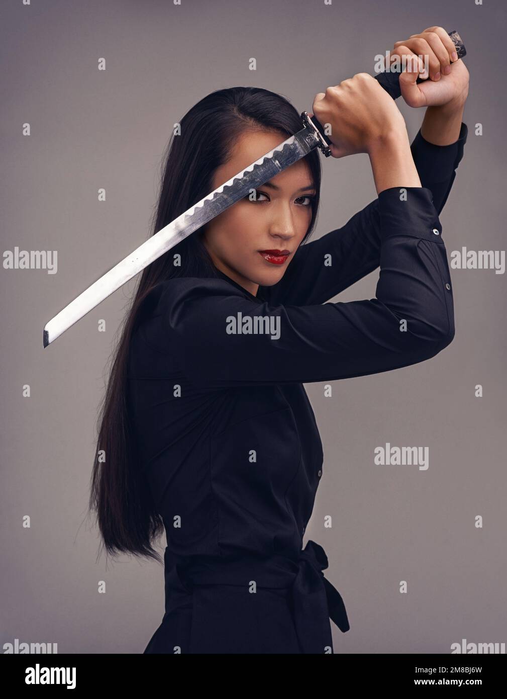 Portrait, épée et samouraï avec une femme modèle en studio sur fond gris pour les arts martiaux ou le combat. Entraînement, fantaisie et arme avec un asiatique Banque D'Images