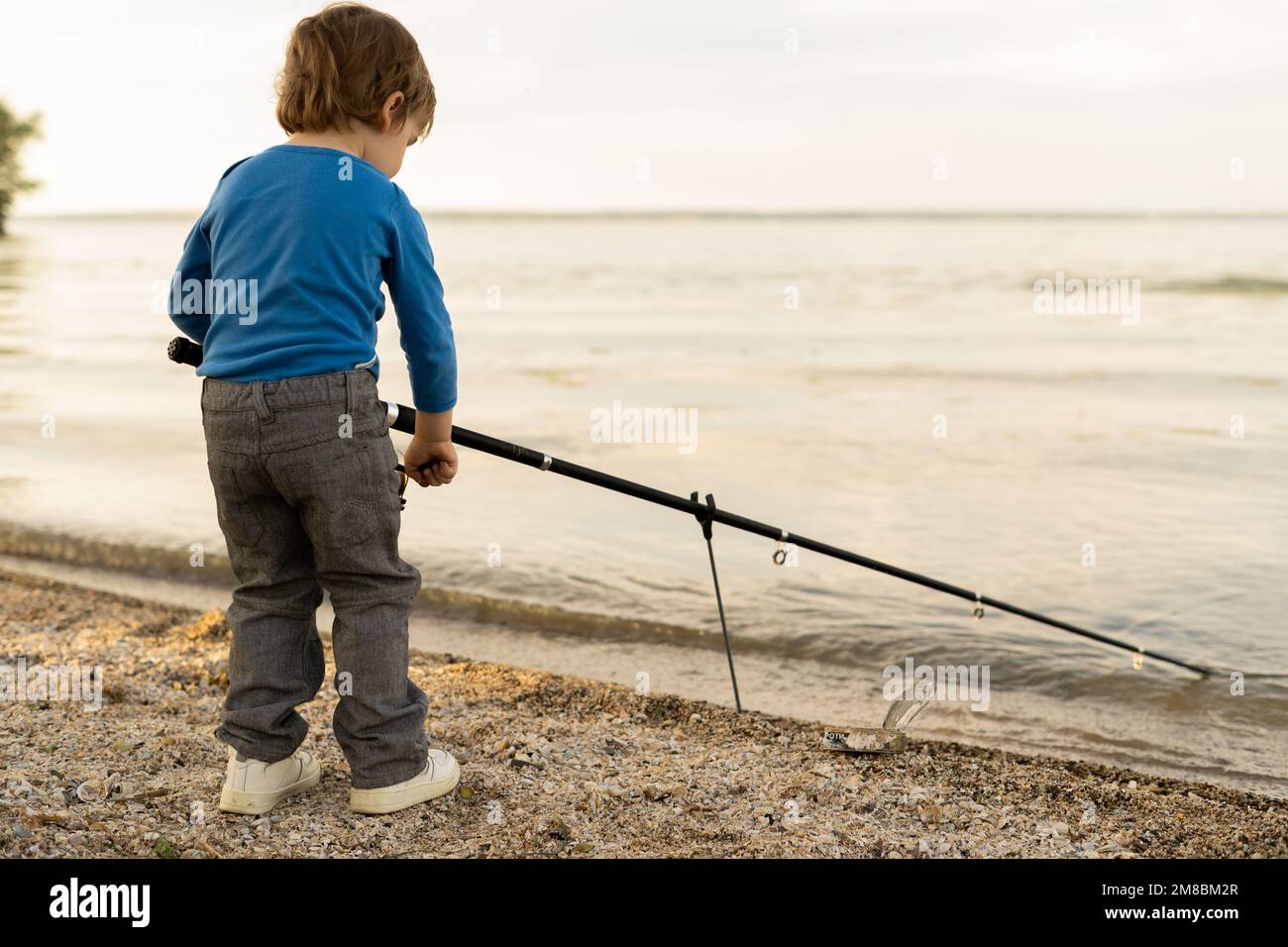 Adorable petit garçon sur la rivière avec pêche à la canne et pêche. petite pêche d'enfant sur le lac. bébé dans la nature Banque D'Images