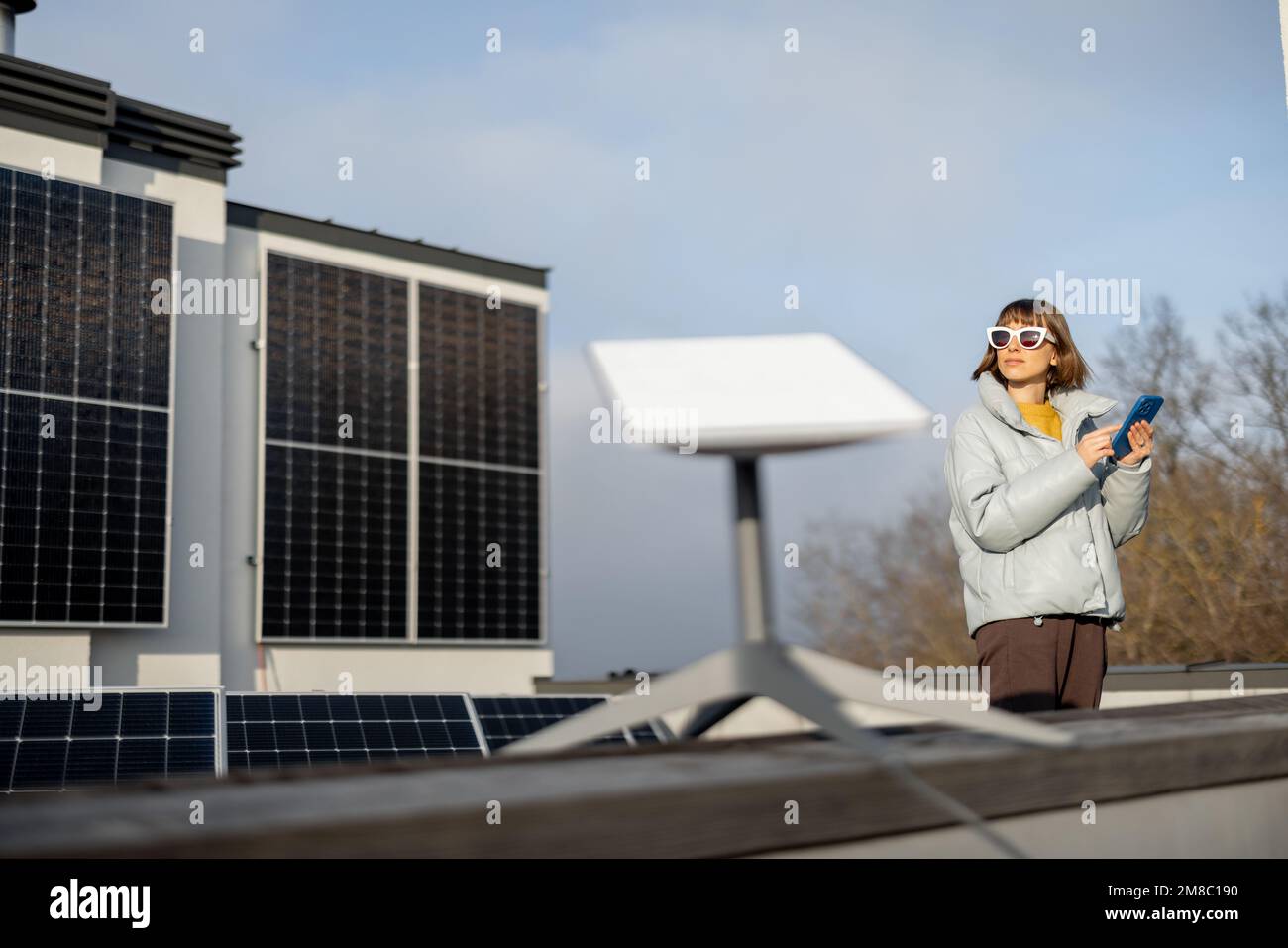 La femme utilise une connexion Internet par satellite sur le toit d'une maison Banque D'Images