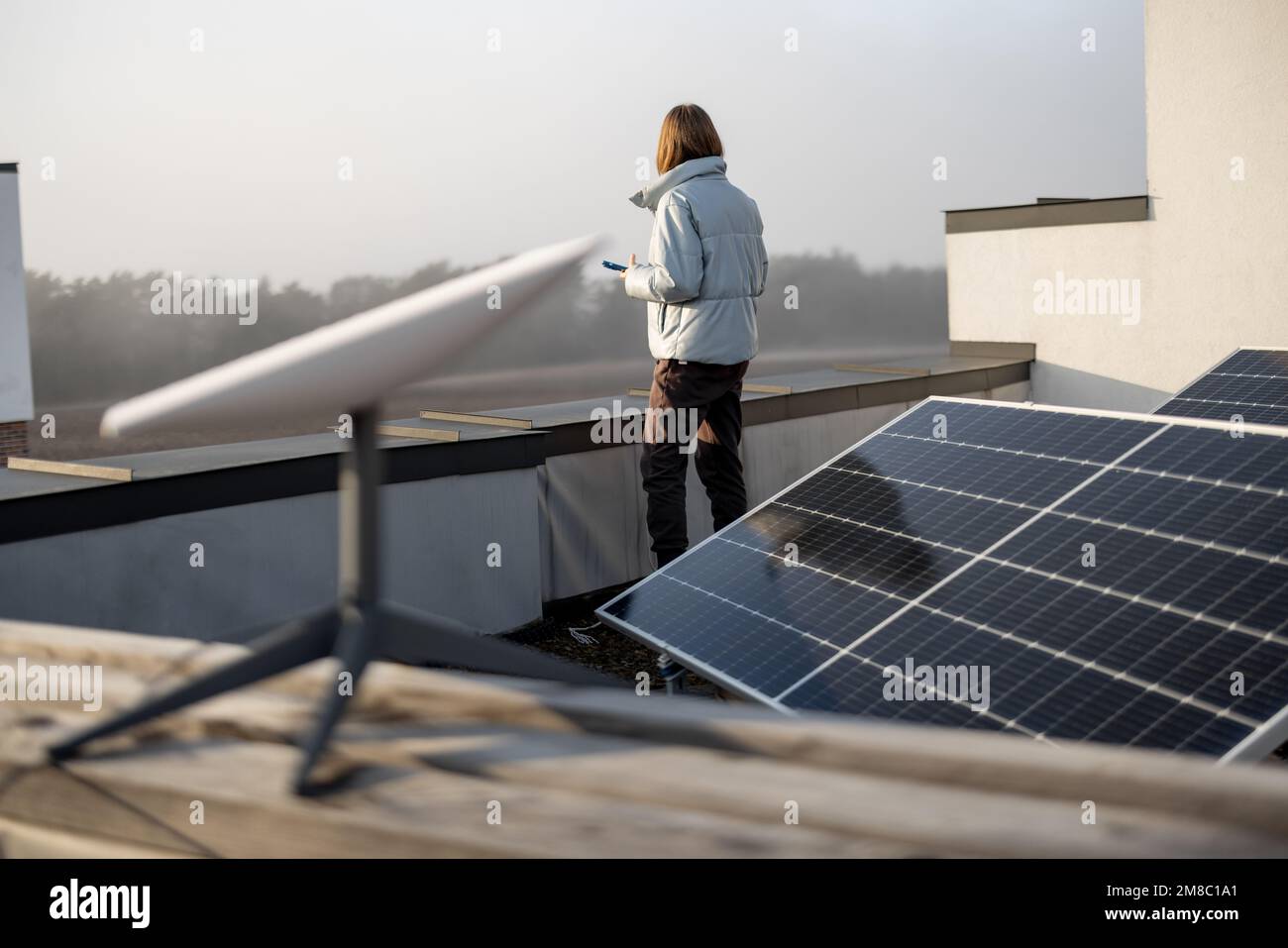 La femme utilise une connexion Internet par satellite sur le toit d'une maison Banque D'Images