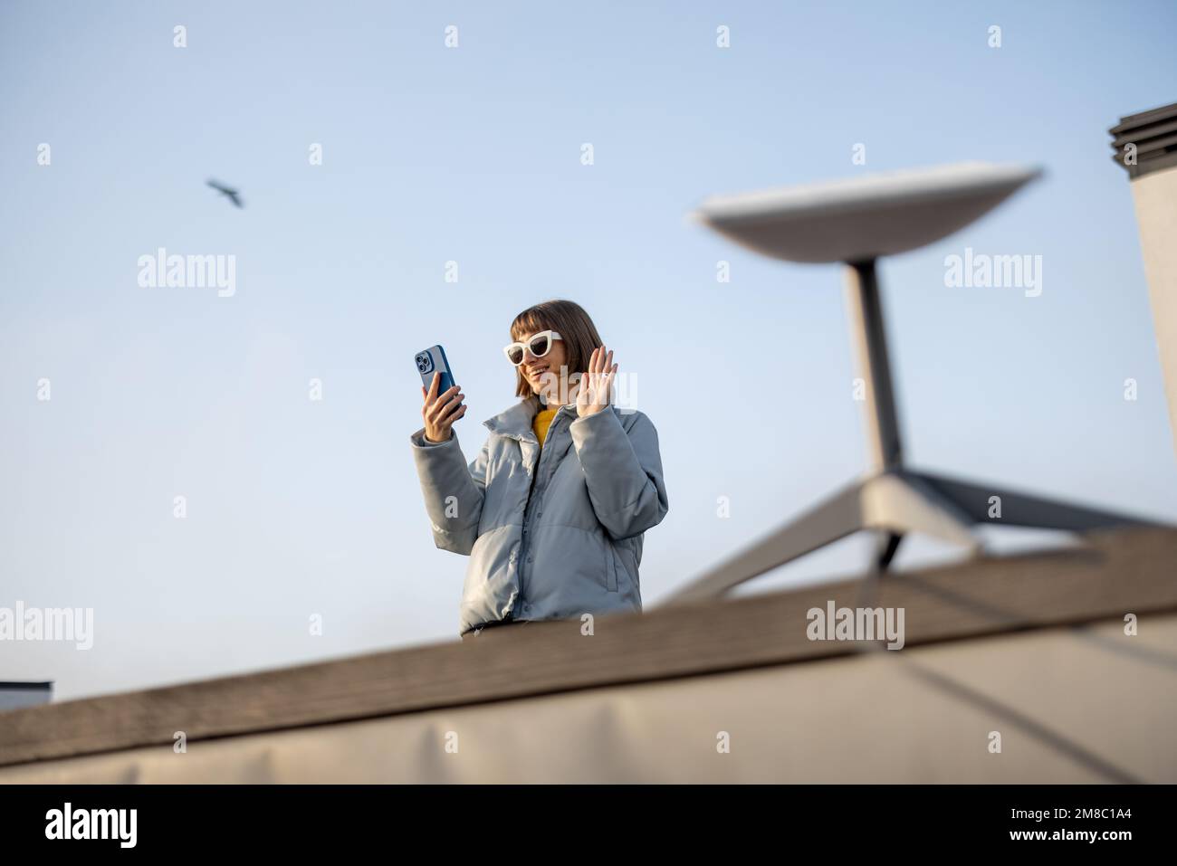 La femme utilise une connexion Internet par satellite sur le toit d'une maison Banque D'Images