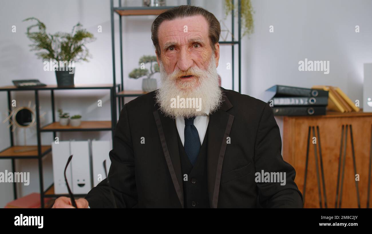 Un homme d'affaires expérimenté et confiant qui prend des lunettes en regardant l'appareil photo avec le sourire sur son lieu de travail à domicile. Portrait en face de grand-père aîné indépendant directeur, travailleur, chef d'entreprise patron homme Banque D'Images