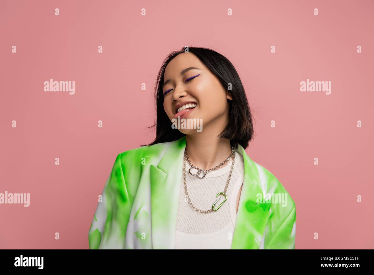 joyeuse femme asiatique dans la veste verte et blanche et colliers en métal  collant hors de la langue isolée sur rose, image de stock Photo Stock -  Alamy