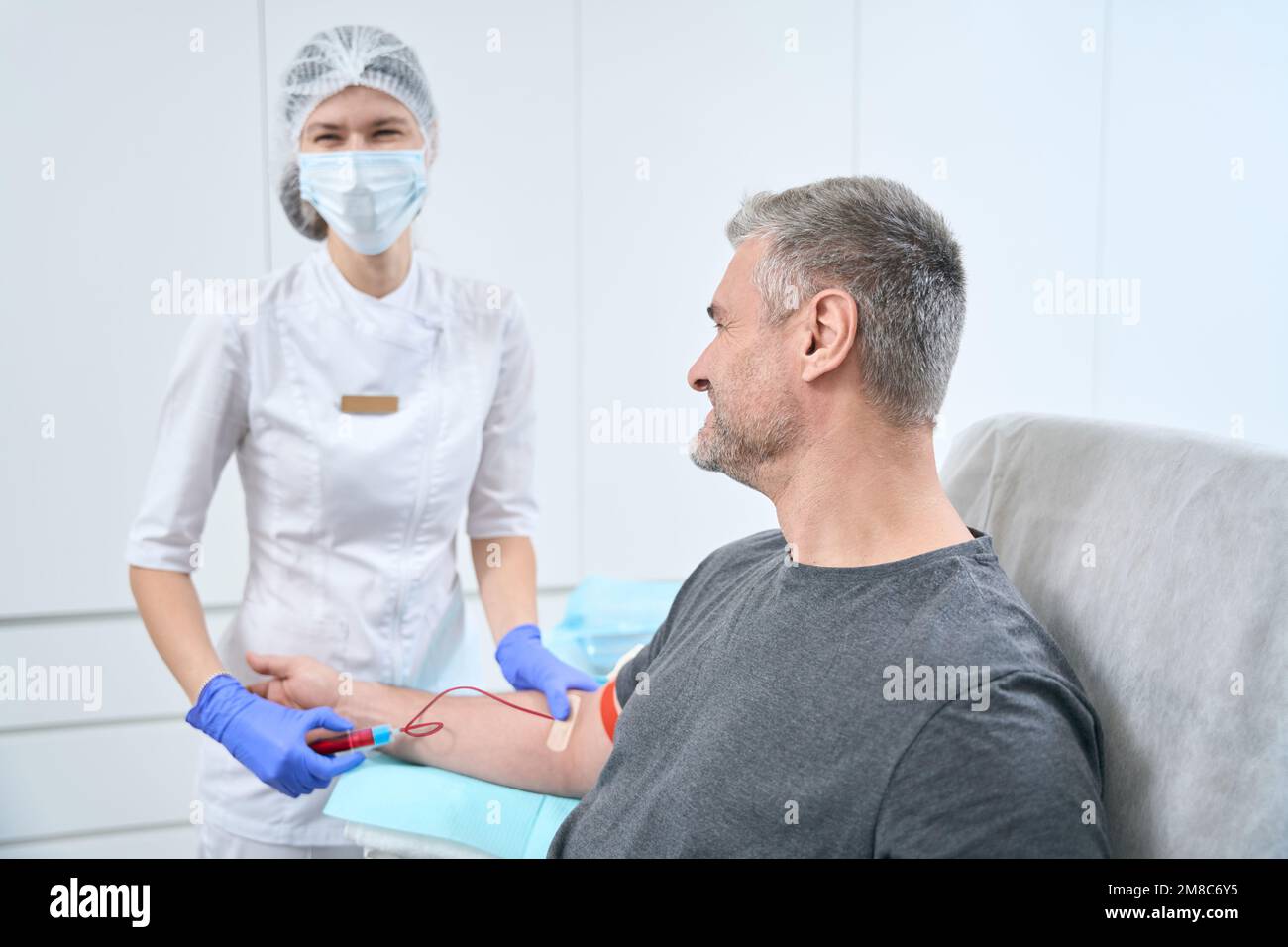 Une infirmière en salle de manipulation stérile prélève l'échantillon de sang du patient Banque D'Images
