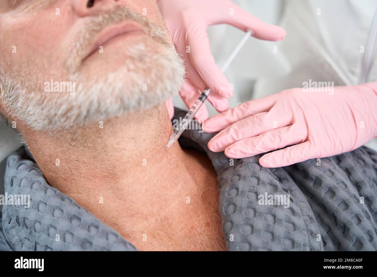 Un travailleur médical fait une injection dans le cou d'un homme Banque D'Images