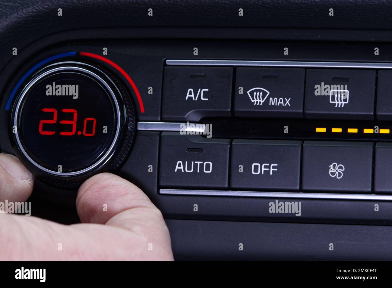 Configurez le climatiseur dans la voiture. La main fait tourner la bague du  climatiseur. L'affichage indique une température de 23,0 degrés celsius à  l'intérieur de la voiture. Air de refroidissement en t