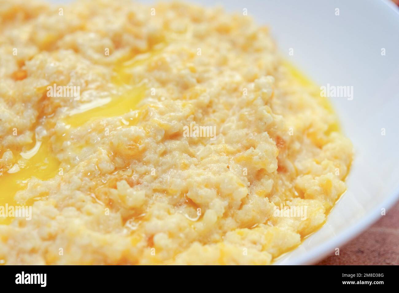 Gros plan de porridge de citrouille avec millet servi dans un bol blanc, foyer sélectif, photo horizontale. Banque D'Images