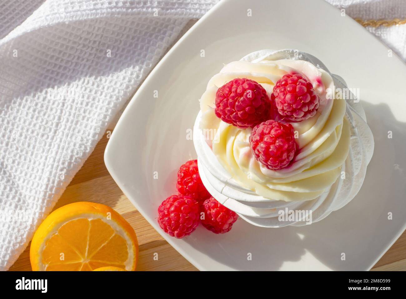 Vue de dessus du gâteau blanc de la mini-meringue Pavlova avec baies de framboises rose sucrées et crème de mascarpone sur l'assiette de la cuisine. Banque D'Images