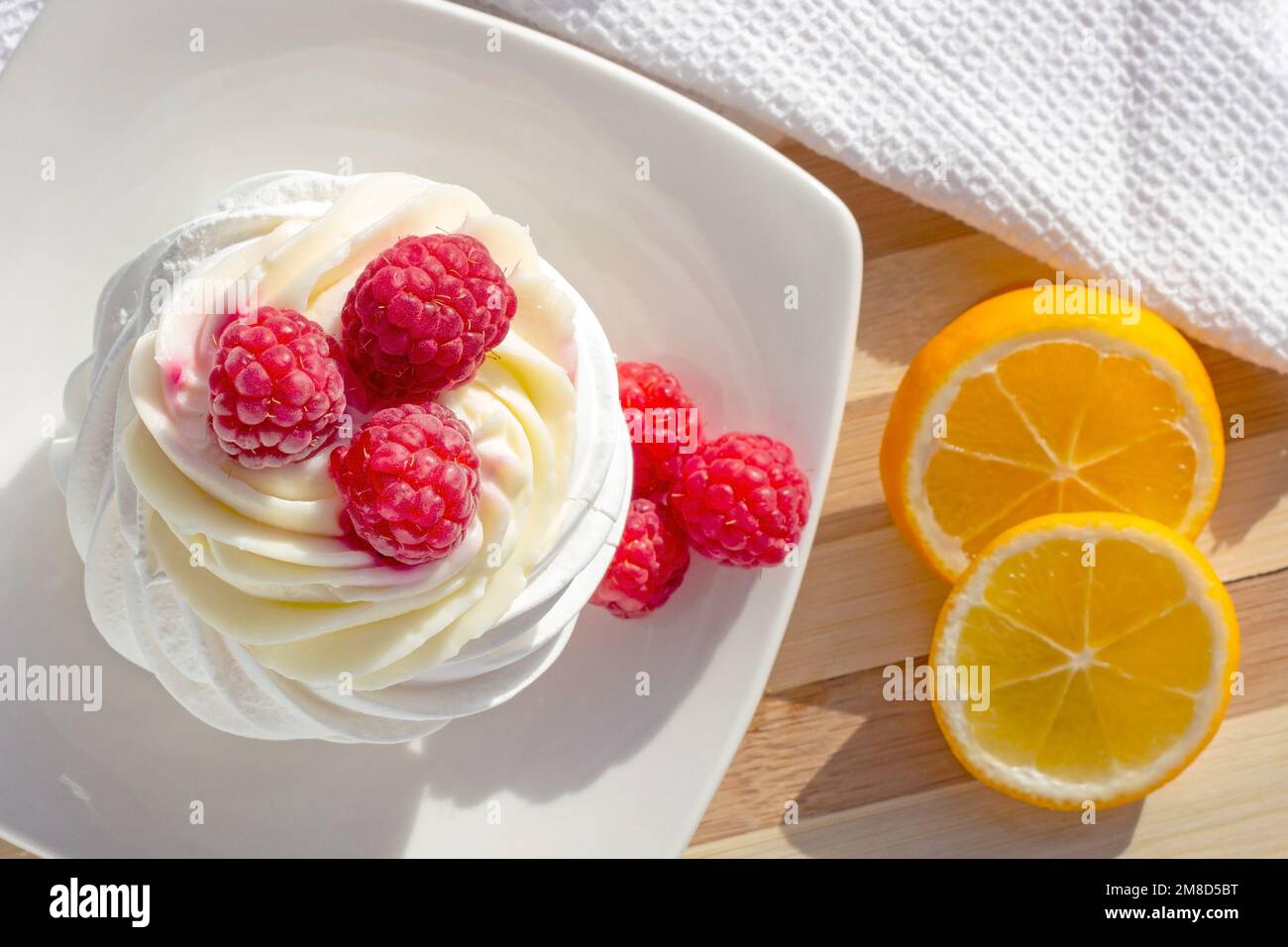 Vue de dessus du gâteau blanc de la mini-meringue Pavlova avec baies de framboises rose sucrées et crème de mascarpone sur l'assiette de la cuisine. Banque D'Images