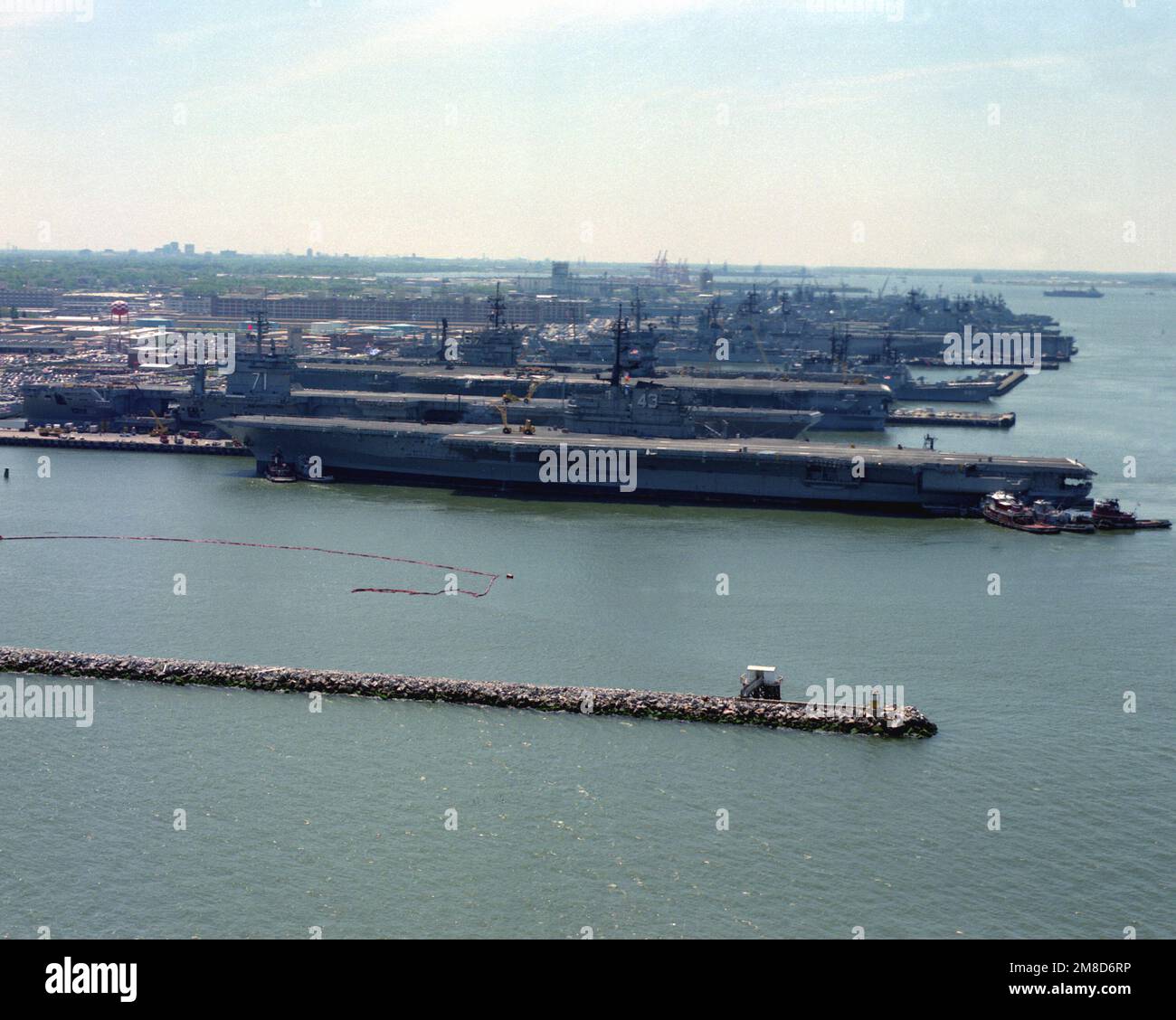 Remorqueurs positionner le porte-avions USS CORAL SEA (CV-43) le long de la jetée n° 12. La MER DE CORAIL devrait être désaffectée sur 30 avril 1990. Parmi les navires en arrière-plan figurent les porte-avions USS THEODORE ROOSEVELT (CVN-71), USS ENTERPRISE (CVN-65), USS JOHN F. KENNEDY (CV-67) et le destroyer USS HAYLER (DD-997). Base: Naval Air Station, Norfolk État: Virginie (va) pays: Etats-Unis d'Amérique (USA) Banque D'Images