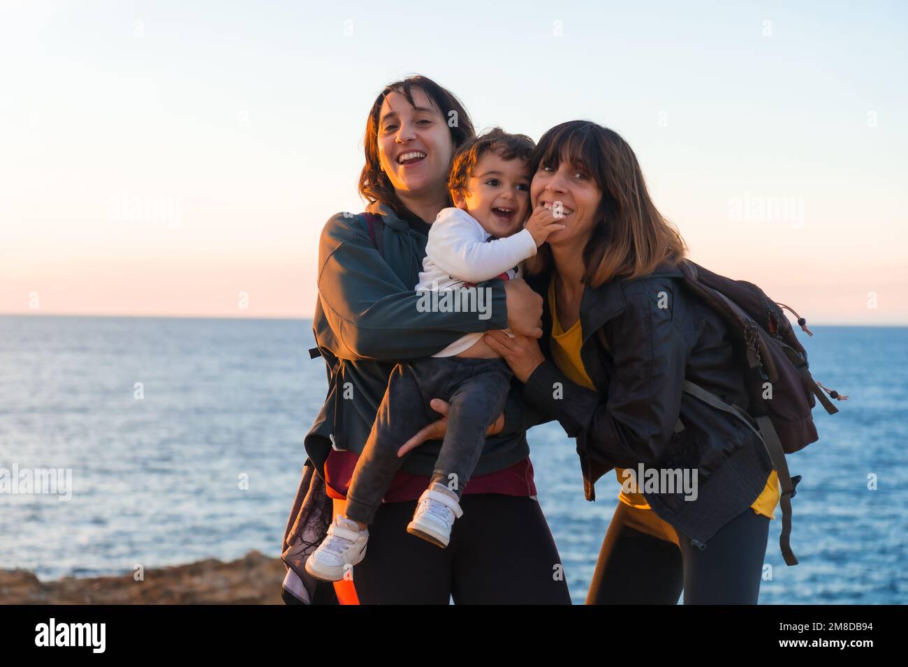 L'tante caucasienne de l'enfant et de la mère l'embrassant sur la côte par  la mer au coucher du soleil Photo Stock - Alamy