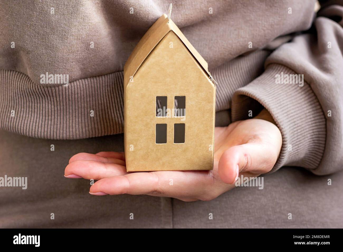 Petite maison de papier dans la main de femme gros plan. Concept d'assurance de biens immobiliers. Banque D'Images