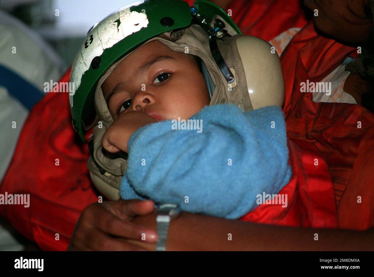 Un enfant est dans les bras de sa mère à bord d'un hélicoptère alors qu'un groupe de personnes évacuées est transporté à Freetown, en Sierra Leone, pendant l'opération Sharp Edge. Les évacués, qui fuient la guerre civile au Libéria, ont d'abord été traités à bord de l'un des navires d'un groupe amphibie prêt à l'emploi qui se trouve en station au large de la côte libérienne. Objet opération/série: SHARP EDGE pays: Océan Atlantique (AOC) Banque D'Images