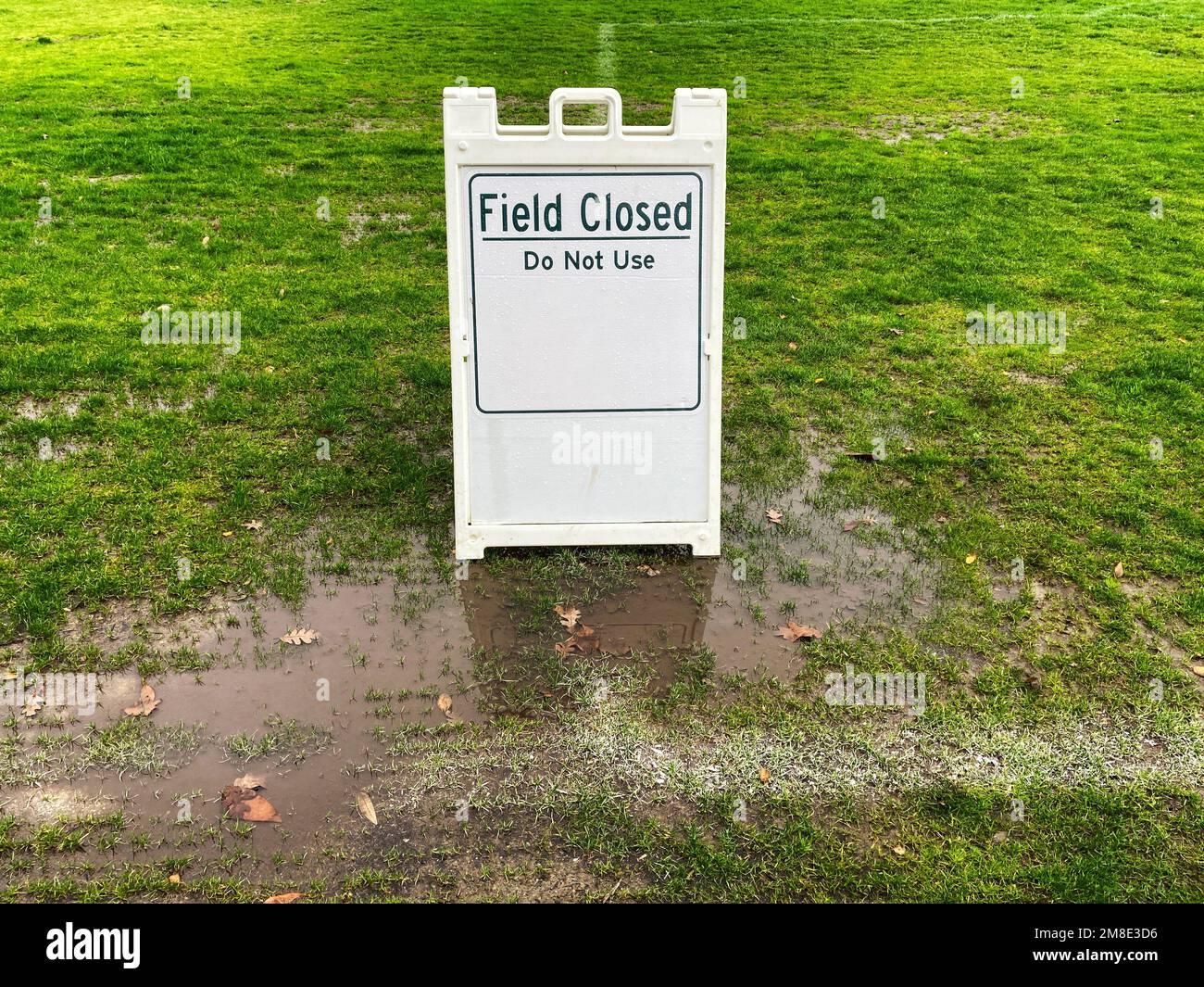 Champ fermé ne pas utiliser de panneau sur une pelouse couverte de flaques vertes dans un parc public en raison des conditions météorologiques Banque D'Images