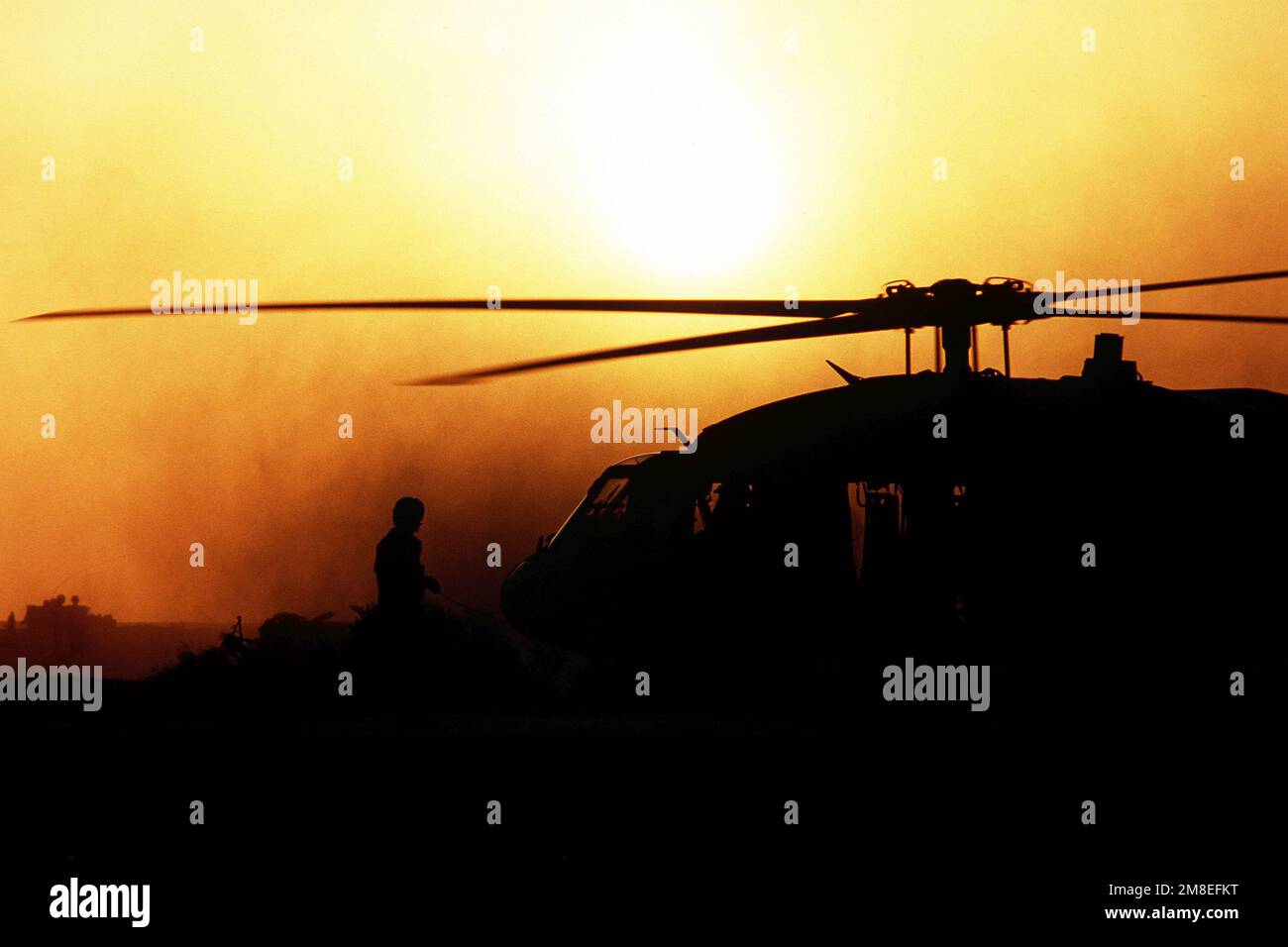 Le chef d'équipage d'un hélicoptère UH-60A Black Hawk (Blackhawk) est silhoueté contre le ciel alors qu'il se tient à bord de l'hélicoptère pendant l'opération Desert Shield. Objet opération/série : BOUCLIER DU DÉSERT pays : Arabie saoudite (SAU) Banque D'Images