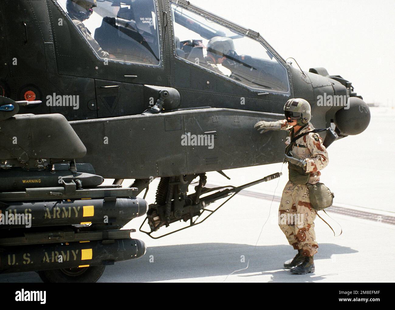 Un avion de la 101st Airborne Division (Air Assault) se trouve à côté d'un hélicoptère Apache AH-64A, prêt pour le décollage pendant l'opération Desert Shield. L'hélicoptère est armé d'un canon automatique M-230A1 30mm sous son poste de pilotage et porte des missiles Hellfire AGM-114 sur son pylône d'aile. Objet opération/série : BOUCLIER DU DÉSERT pays : Arabie saoudite (SAU) Banque D'Images